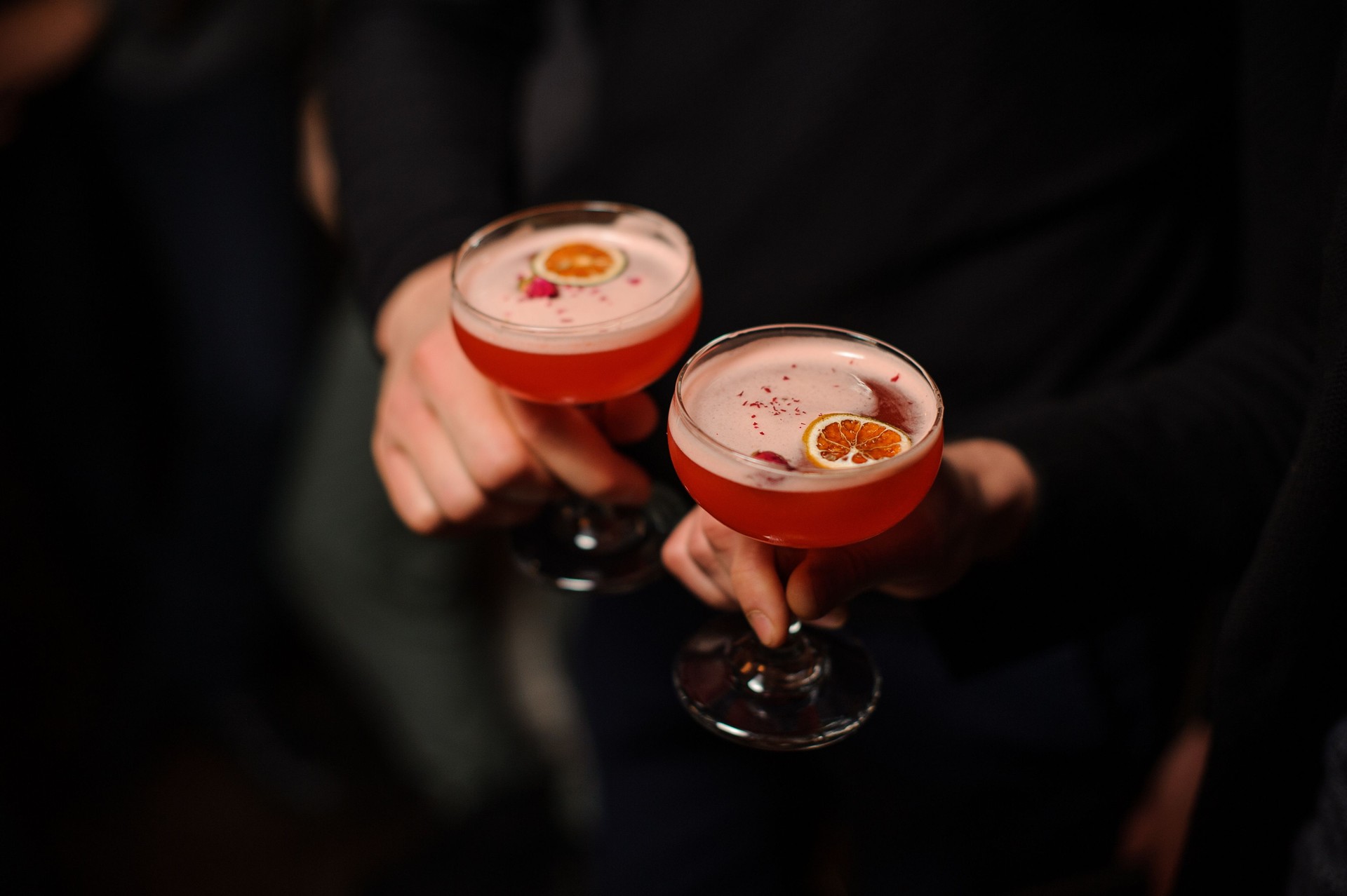 Two people holding cocktail glasses with sweet alcoholic drink