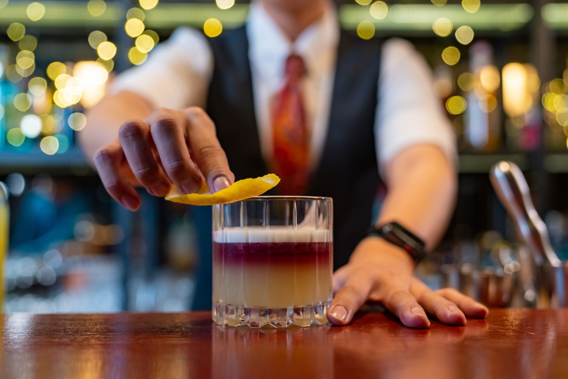 Professional bartender preparing alcoholic cocktail serving  to customers at bar.